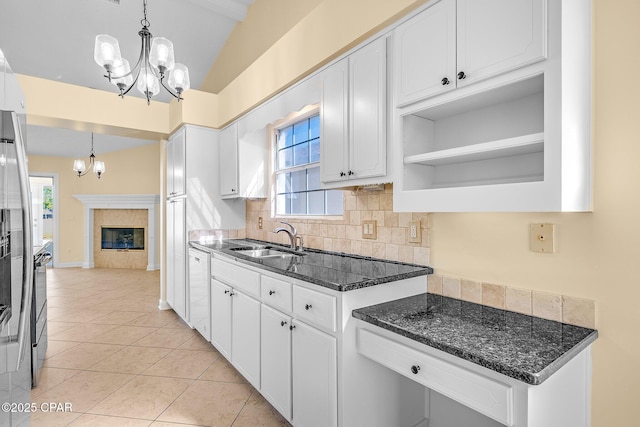 kitchen featuring dark stone counters, white cabinetry, a fireplace, and pendant lighting