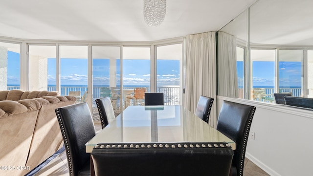 tiled dining area featuring a water view and a chandelier