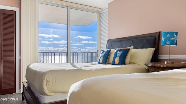 bedroom featuring access to exterior, a water view, and wood-type flooring