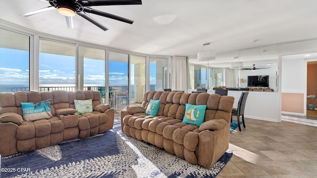 living room featuring ceiling fan, a water view, and a wall of windows