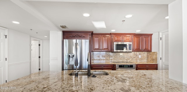 kitchen featuring light stone countertops, stainless steel appliances, tasteful backsplash, and sink