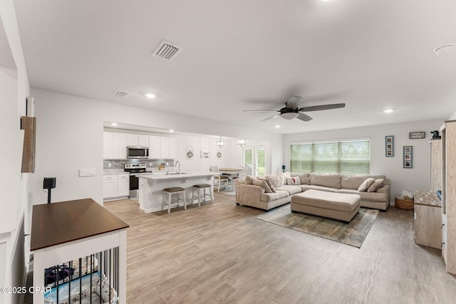 living room with ceiling fan, light hardwood / wood-style flooring, and sink