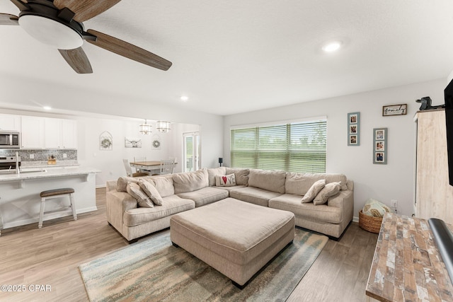 living room featuring light hardwood / wood-style flooring, ceiling fan, and sink