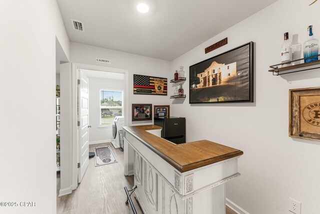 corridor with washer and dryer and light hardwood / wood-style floors