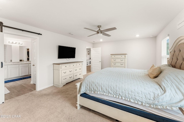 bedroom with ceiling fan, light carpet, and ensuite bath