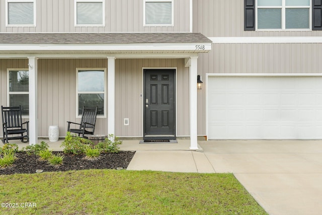 doorway to property featuring a lawn, covered porch, and a garage