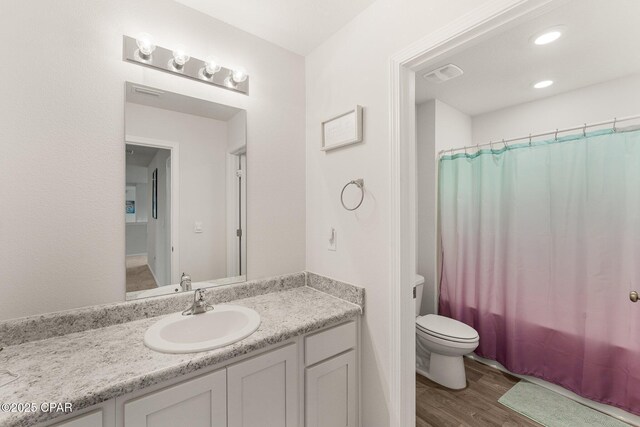 full bathroom featuring hardwood / wood-style flooring, vanity, shower / bath combo, and toilet