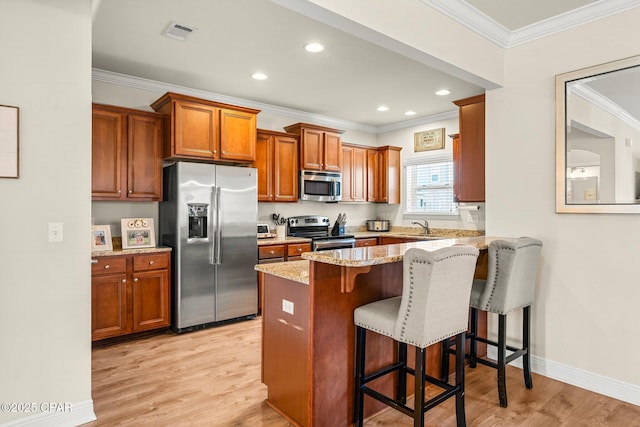 kitchen with a breakfast bar, light stone countertops, crown molding, and appliances with stainless steel finishes