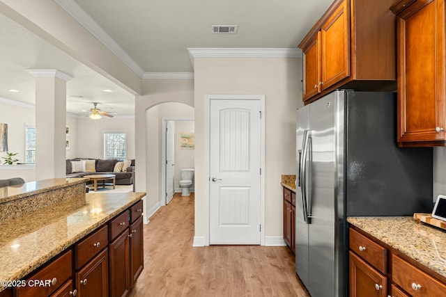 kitchen with ceiling fan, stainless steel fridge, light stone counters, and ornamental molding