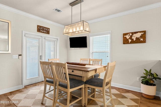 dining area featuring a healthy amount of sunlight, light hardwood / wood-style floors, and crown molding