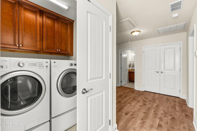 washroom with cabinets, light wood-type flooring, and independent washer and dryer