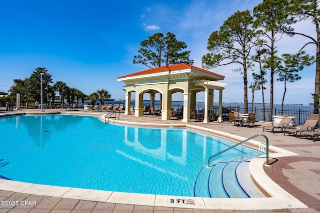 view of swimming pool with a water view and a patio area