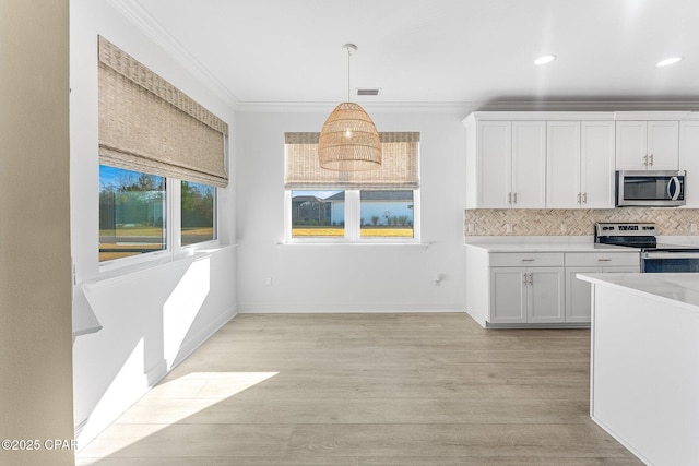 kitchen featuring light countertops, stainless steel appliances, white cabinetry, backsplash, and ornamental molding