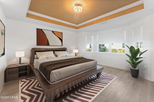 bedroom with visible vents, crown molding, wood finished floors, and a tray ceiling