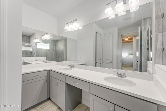 full bath with a sink, wood finished floors, double vanity, and a chandelier