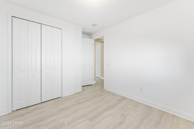 unfurnished bedroom featuring a closet, baseboards, and light wood-type flooring