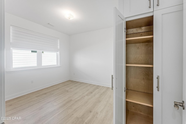 unfurnished bedroom with baseboards, light wood finished floors, and visible vents