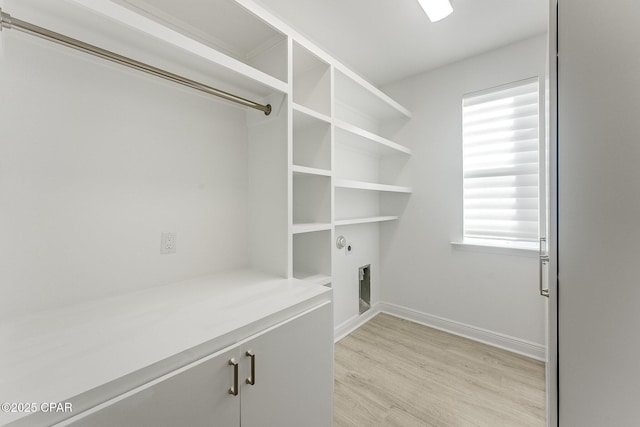laundry room featuring laundry area, light wood-style floors, hookup for an electric dryer, and a healthy amount of sunlight