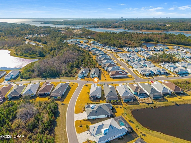 aerial view featuring a wooded view, a water view, and a residential view