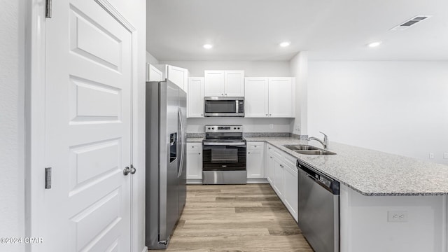 kitchen with white cabinets, light wood-type flooring, appliances with stainless steel finishes, and sink