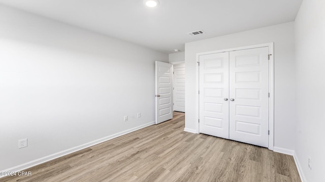 unfurnished bedroom with light wood-type flooring and a closet