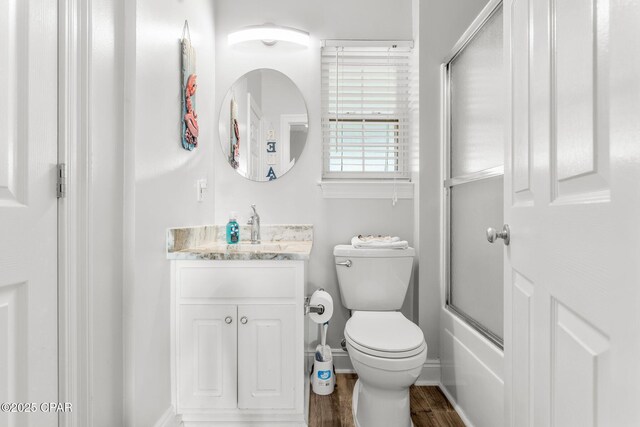 full bathroom with wood-type flooring, vanity, toilet, and bath / shower combo with glass door