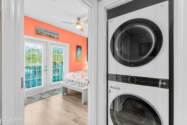 laundry room with ceiling fan, stacked washer and dryer, and light wood-type flooring