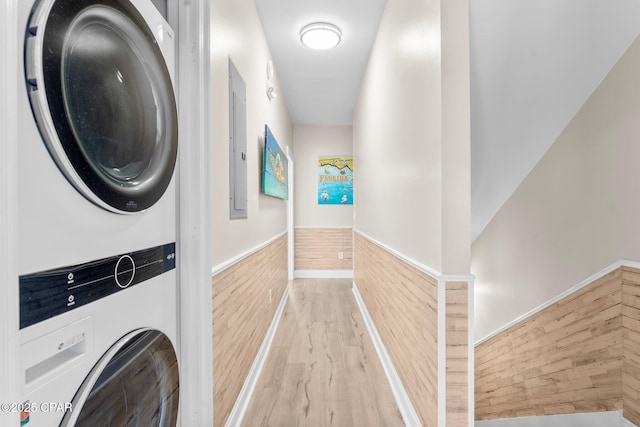 laundry room with wood walls, light hardwood / wood-style floors, and stacked washer / drying machine