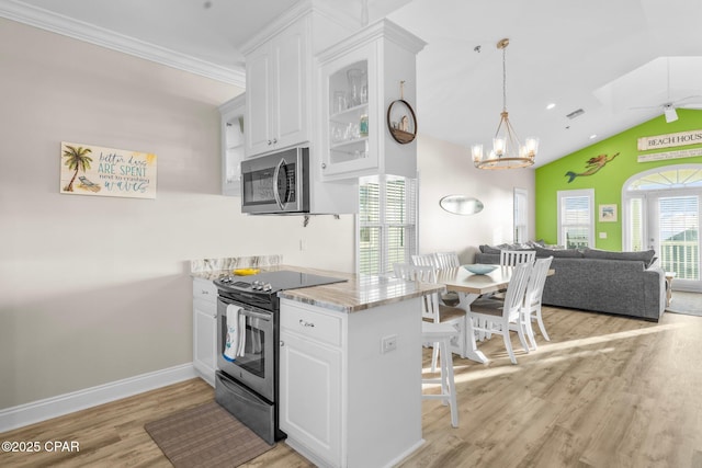 kitchen with a breakfast bar, white cabinets, vaulted ceiling, light wood-type flooring, and appliances with stainless steel finishes