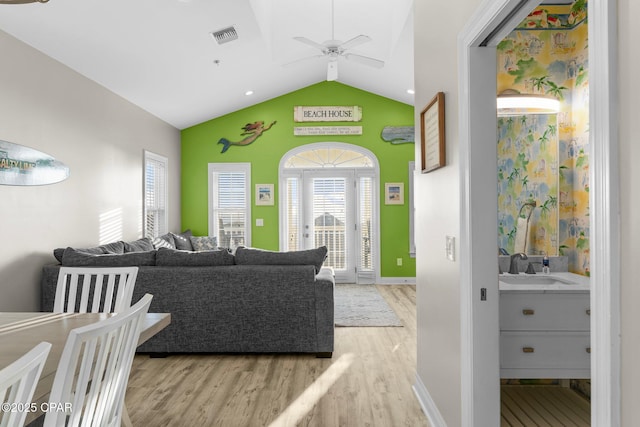 living room with light hardwood / wood-style floors, vaulted ceiling, ceiling fan, and sink