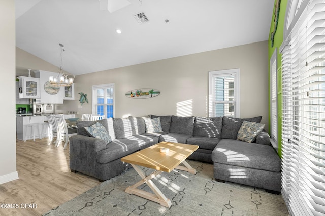 living room featuring a chandelier, light hardwood / wood-style floors, and lofted ceiling