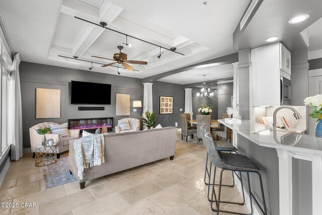 kitchen with white cabinetry, premium appliances, light stone counters, ventilation hood, and a tray ceiling