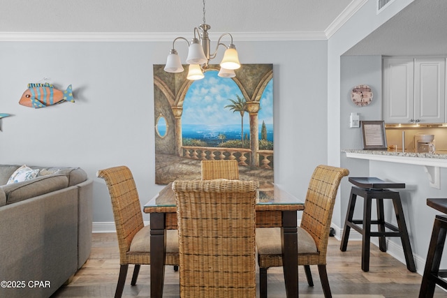 dining area with light hardwood / wood-style floors, crown molding, and a chandelier