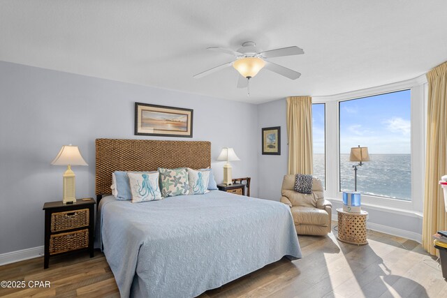 bedroom featuring ceiling fan, a water view, and wood-type flooring