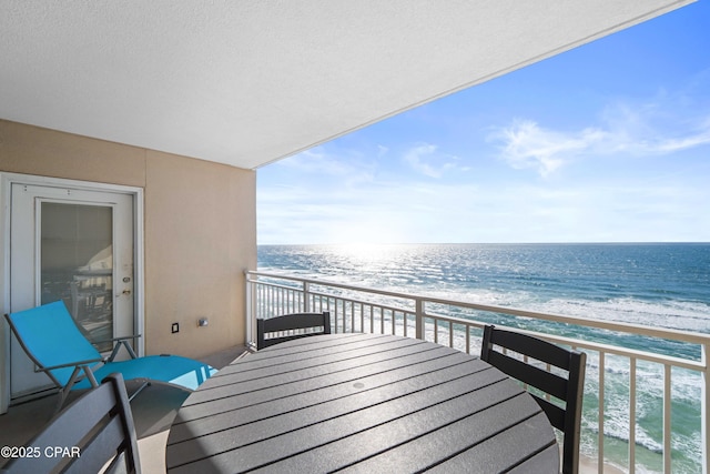 balcony with a water view and a view of the beach