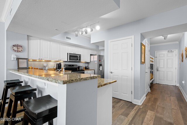 kitchen featuring white cabinets, kitchen peninsula, stainless steel appliances, and a textured ceiling