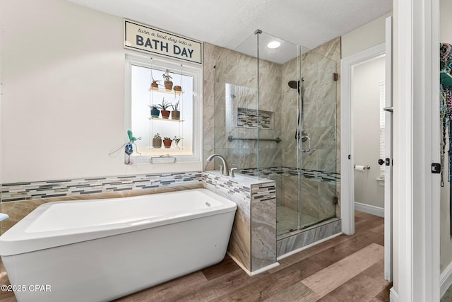 bathroom featuring shower with separate bathtub, a textured ceiling, and hardwood / wood-style flooring