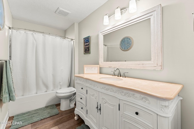 full bathroom featuring vanity, shower / bath combo, hardwood / wood-style flooring, toilet, and a textured ceiling