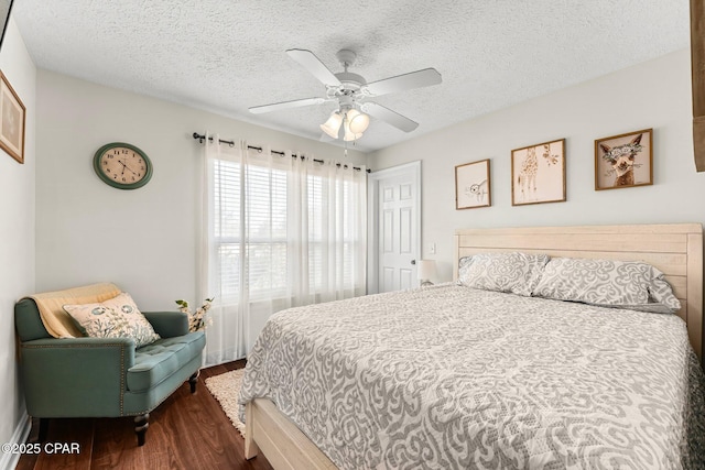 bedroom with ceiling fan, dark hardwood / wood-style flooring, and a textured ceiling