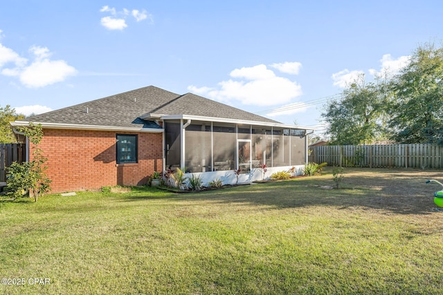 rear view of house featuring a yard and a sunroom