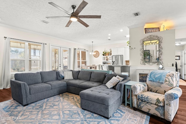 living room with wood-type flooring, a textured ceiling, ceiling fan, and crown molding