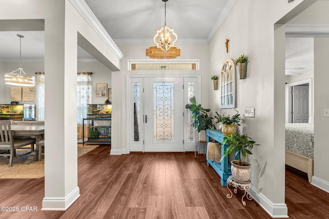 entryway with a notable chandelier, wood-type flooring, ornamental molding, and a textured ceiling