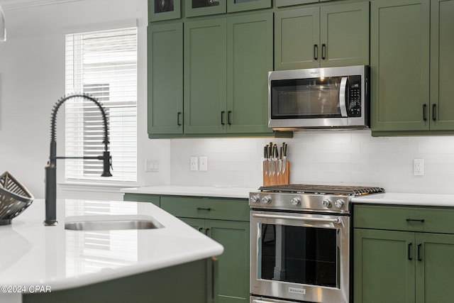 kitchen with appliances with stainless steel finishes, green cabinetry, plenty of natural light, sink, and backsplash