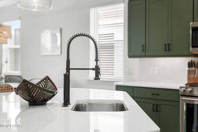 kitchen with stainless steel appliances, green cabinetry, and sink