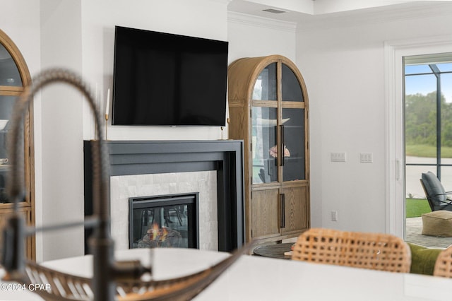 living room featuring a tiled fireplace and crown molding