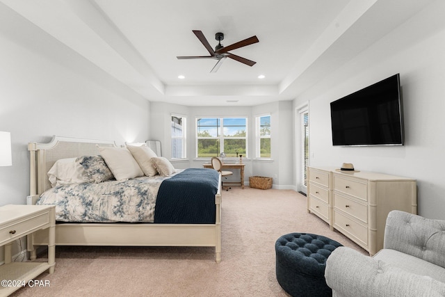 carpeted bedroom with ceiling fan and a raised ceiling