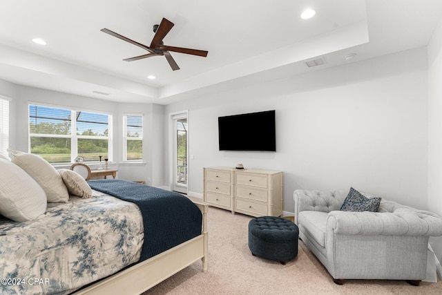 bedroom with ceiling fan, multiple windows, light carpet, and a raised ceiling