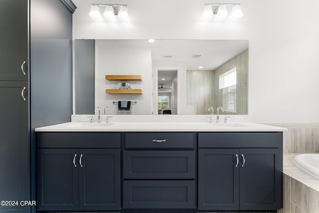 bathroom featuring tiled bath and vanity