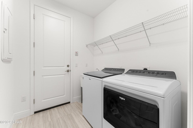 laundry room with washing machine and clothes dryer and light hardwood / wood-style floors