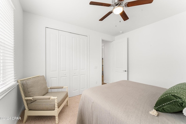 bedroom with a closet, ceiling fan, and light colored carpet